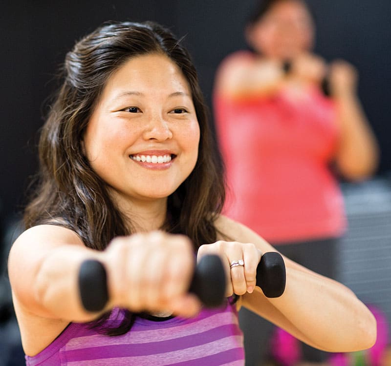 Woman exercising with light weights in fitness class